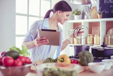 Mutfakta sobanın yanında duran genç bir kadın.