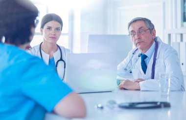 Parlak bir ofiste çalışan ciddi bir tıbbi ekip.