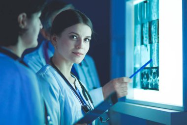 Bir grup doktor bir klinikte röntgenleri inceliyor, teşhis koymayı düşünüyorlar.
