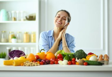 Ahşap iç kısımda meyve ve sebze dolu masada oturan genç ve tatlı bir kadın..