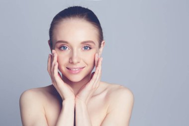 Yüzüne dokunan doğal makyajlı güzel bir kadının portresi..