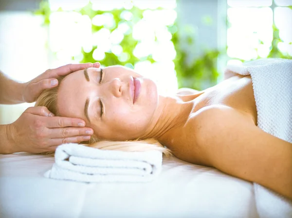 Hermosa y saludable mujer joven relajante con masaje facial en el salón de spa de belleza — Foto de Stock