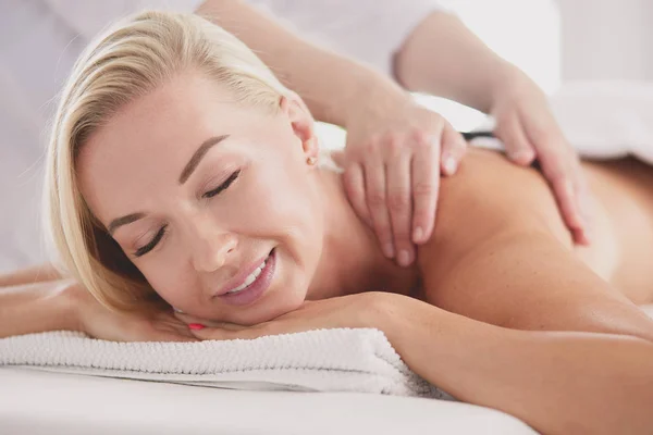 Ung kvinna i spa salong, få stenar massage — Stockfoto