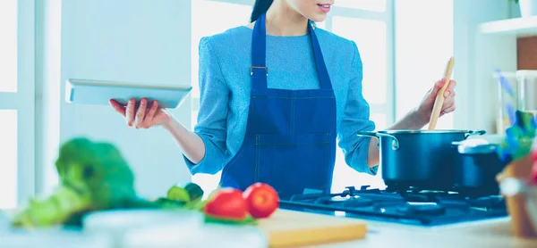 Junge Frau kocht mit Tablet-Computer in ihrer Küche — Stockfoto