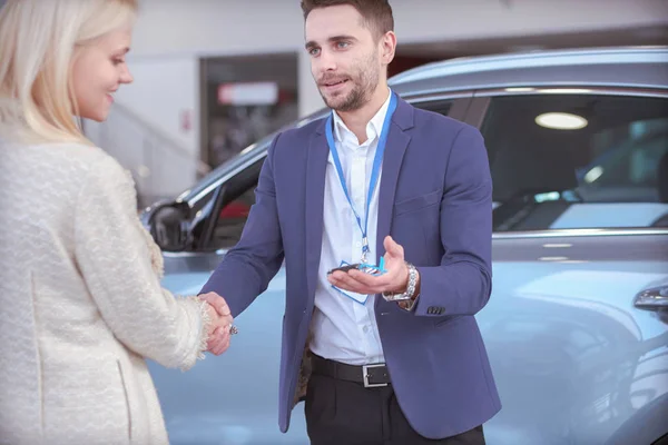 Vendedor de carro vende um carro ao cliente feliz na concessionária de carro e entrega as chaves. — Fotografia de Stock