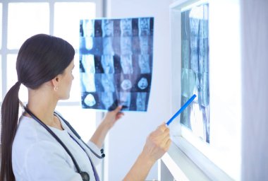 Stetoskop lu genç gülümseyen kadın doktor doktor ofisinde röntgeni işaret ediyor