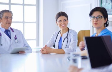 Ciddi bir tıbbi ekip hastaları parlak bir ofiste tartışıyor.