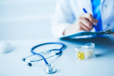 Kadınların elleri bir kağıt parçasına yazı yazıp masasında kalem bırakırlar.