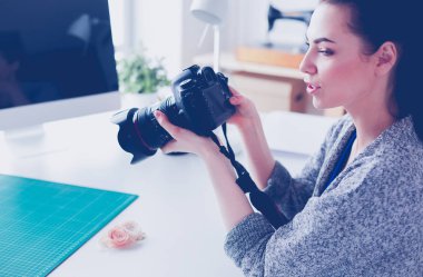 İşyerinin yanında duran ve dijital fotoğraf makinesinde fotoğraflayan genç kadın tasarımcı