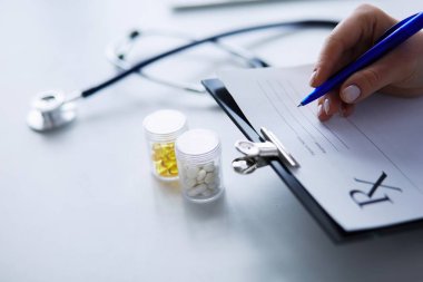 Kadınların elleri bir kağıt parçasına yazı yazıp masasında kalem bırakırlar.