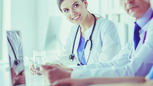 Medico sorridente che utilizza un computer portatile che lavora con i suoi colleghi in una luminosa stanza d'ospedale — Foto Stock