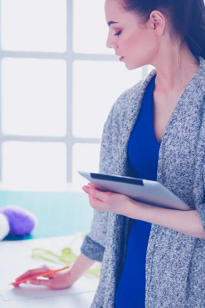 Bella giovane donna che lavora su tablet digitale e sorride mentre si siede al suo posto di lavoro — Foto Stock