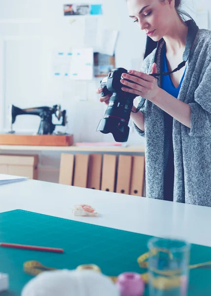 Giovane donna designer in piedi vicino al posto di lavoro e fotografarlo sulla macchina fotografica digitale — Foto Stock