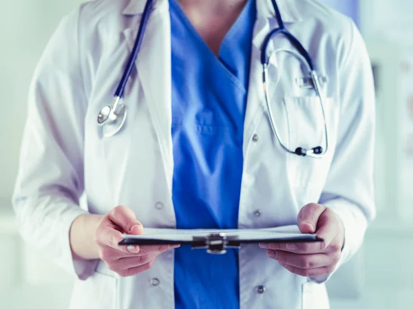 Médico sonriente con una carpeta en uniforme de pie — Foto de Stock