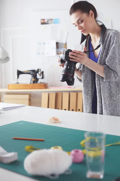 Giovane designer donna scattare foto con fotocamera digitale mentre in piedi vicino alla scrivania nel suo laboratorio — Foto Stock
