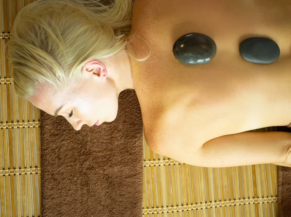 Jonge vrouw in spa salon, het krijgen van stenen massage — Stockfoto