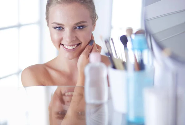 Giovane donna in accappatoio guardando nello specchio del bagno — Foto Stock