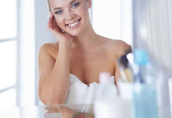 Jonge vrouw in badjas op zoek in badkamer spiegel — Stockfoto