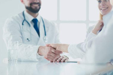 Doktor ofiste erkek bir hastayla el sıkışıyor.
