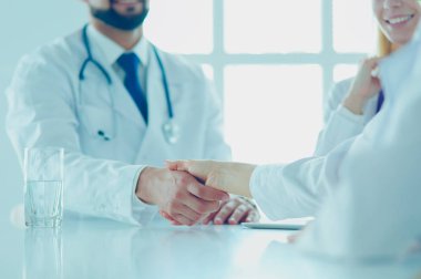 Doktor ofiste erkek bir hastayla el sıkışıyor.