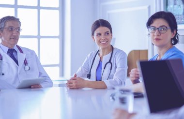 Ciddi bir tıbbi ekip hastaları parlak bir ofiste tartışıyor.