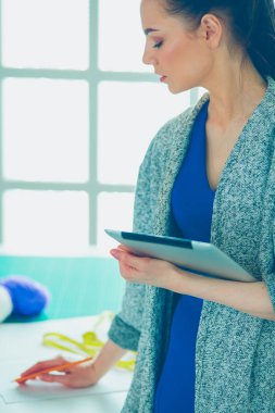 Güzel genç bir kadın dijital tablet üzerinde çalışıyor ve çalışırken gülümsüyor.