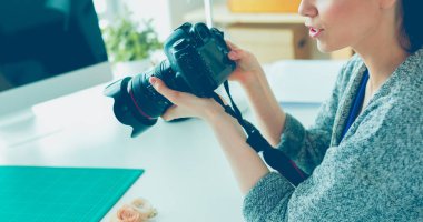 İşyerinin yanında duran ve dijital fotoğraf makinesinde fotoğraflayan genç kadın tasarımcı