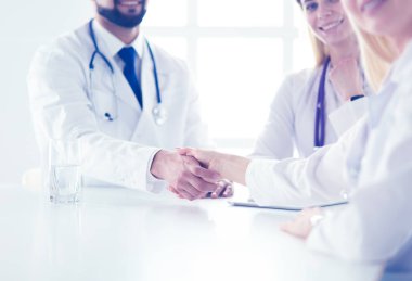 Doktor ofiste erkek bir hastayla el sıkışıyor.