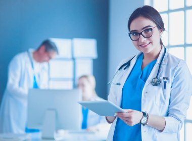 Hastane lobisinde tablet bilgisayar kullanan kadın doktor.