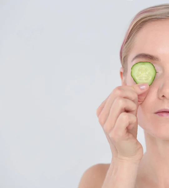 Mooie jongedame met plakjes komkommer op witte achtergrond. — Stockfoto