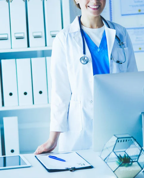 Jeune médecin femme debout près de la table, isolée sur fond blanc — Photo