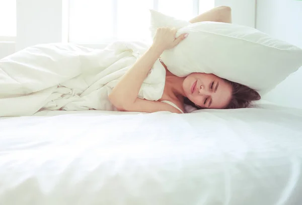 Joven mujer caucásica cubriendo su cabeza y orejas con almohadas . —  Fotos de Stock