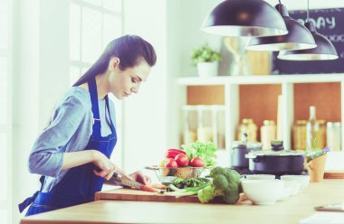 Mutfakta sebze doğrayan genç bir kadın.