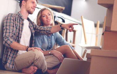 Genç bir çift yeni ev içinde hareket. Oturma ve açma sonra rahatlatıcı. Bir şey üstünde laptop arıyorum. Genç Çift