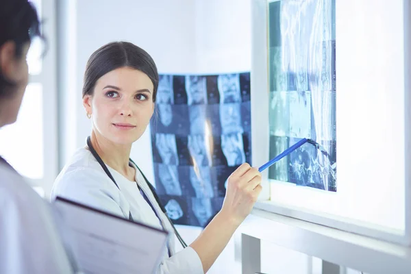 Zwei lächelnde Ärzte zeigen auf Röntgenbilder im Sprechzimmer eines Krankenhauses — Stockfoto