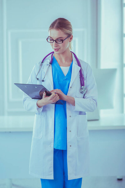 Smiling female doctor with a folder in uniform standing