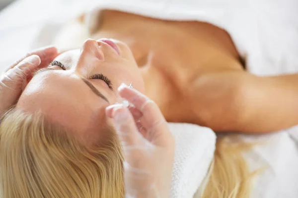 Hermosa mujer haciendo masaje facial en un salón de spa . — Foto de Stock