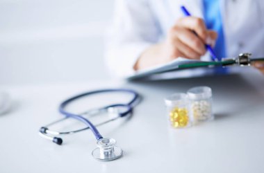 Kadınların elleri bir kağıt parçasına yazı yazıp masasında kalem bırakırlar.