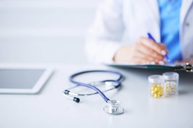 Kadınların elleri bir kağıt parçasına yazı yazıp masasında kalem bırakırlar.