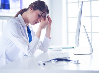 İş yerinde baş ağrısı çeken genç bir kadın doktorun portresi.