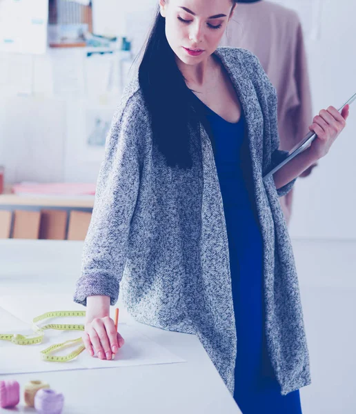 Hermosa joven que trabaja en una tableta digital y sonríe mientras está sentada en su lugar de trabajo — Foto de Stock