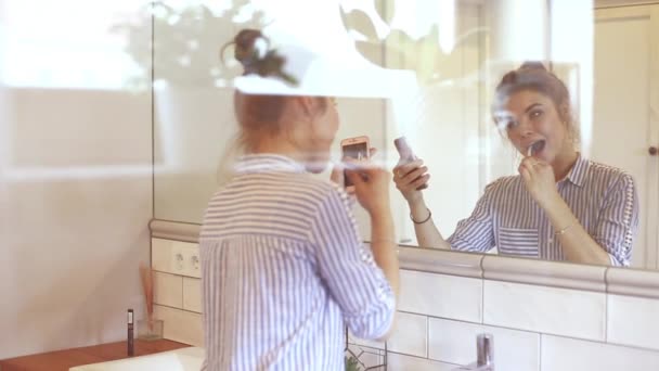 Дівчина чистить зуби і за допомогою мобільного телефону — стокове відео