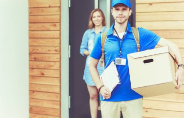 Mavi üniformalı gülümseyen kurye servis konseptine paket kutusu teslim eden teslimatçı. Mavi üniformalı gülümseyen teslimatçı.