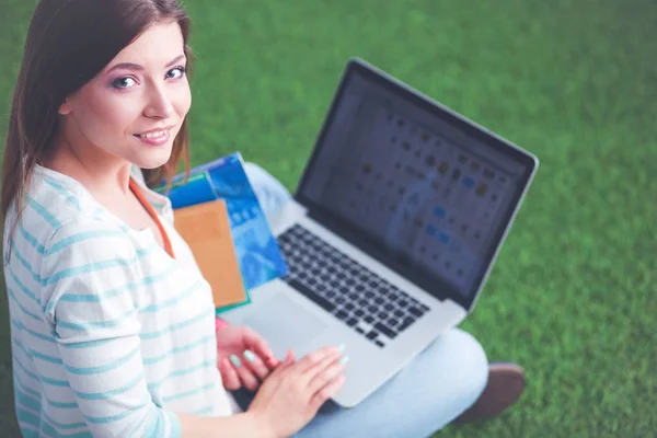 緑の芝生の上に座ってノートパソコンを持つ若い女性。ポートレート若い女性 — ストック写真