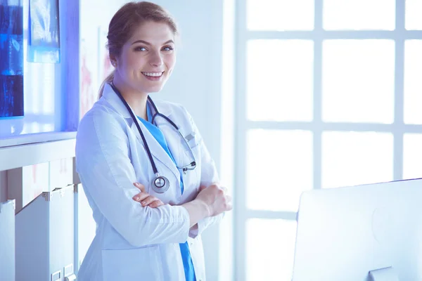 Jeune femme médecin en uniforme blanc debout dans le bureau des cliniques — Photo