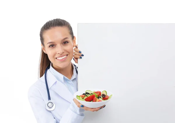 Portré egy gyönyörű doktornőről, aki tányért tart friss zöldségekkel, közel az ürességhez. Női orvosok — Stock Fotó