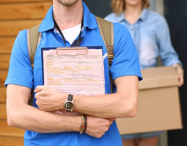 Repartidor sonriente con uniforme azul que entrega la caja de paquetes al destinatario: concepto de servicio de mensajería. Repartidor sonriente en uniforme azul —  Fotos de Stock