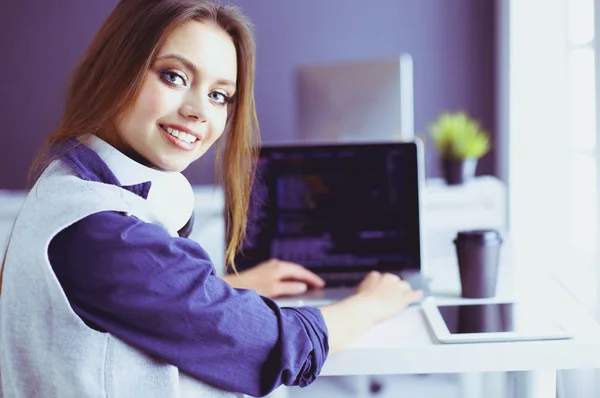 Ung självsäker affärskvinna som arbetar på kontoret skrivbord och skriva med en bärbar dator — Stockfoto