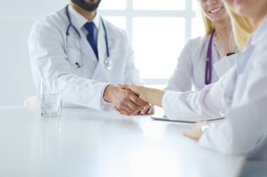 Doktor ofiste erkek bir hastayla el sıkışıyor.