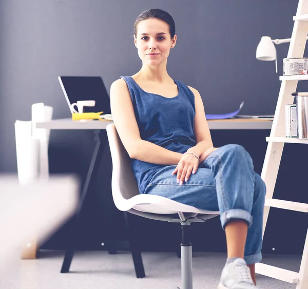 Jonge vrouw zit aan het bureau met instrumenten, plan en laptop. — Stockfoto